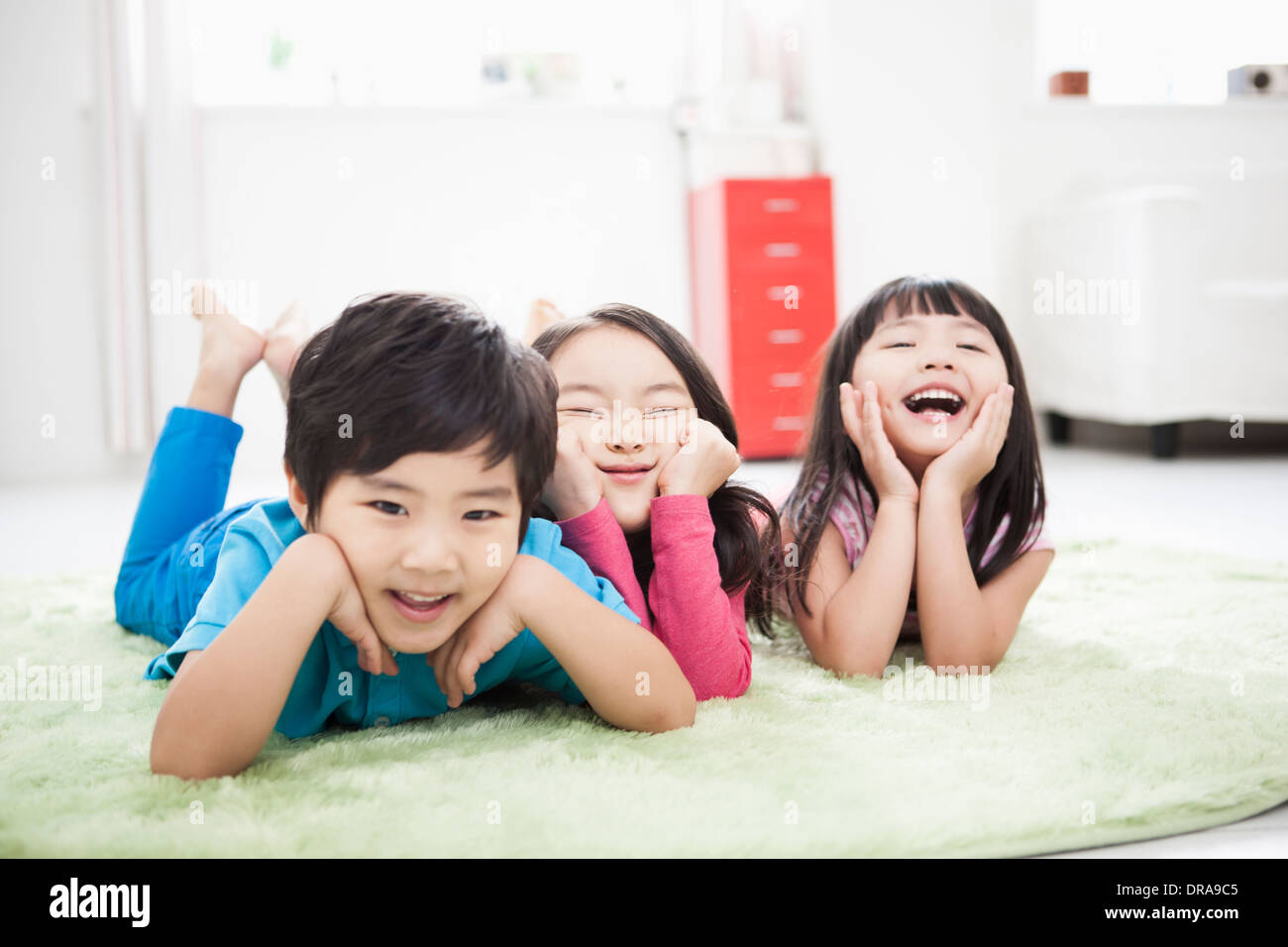 kids lying in the floor carpet with hands under their chin Stock Photo