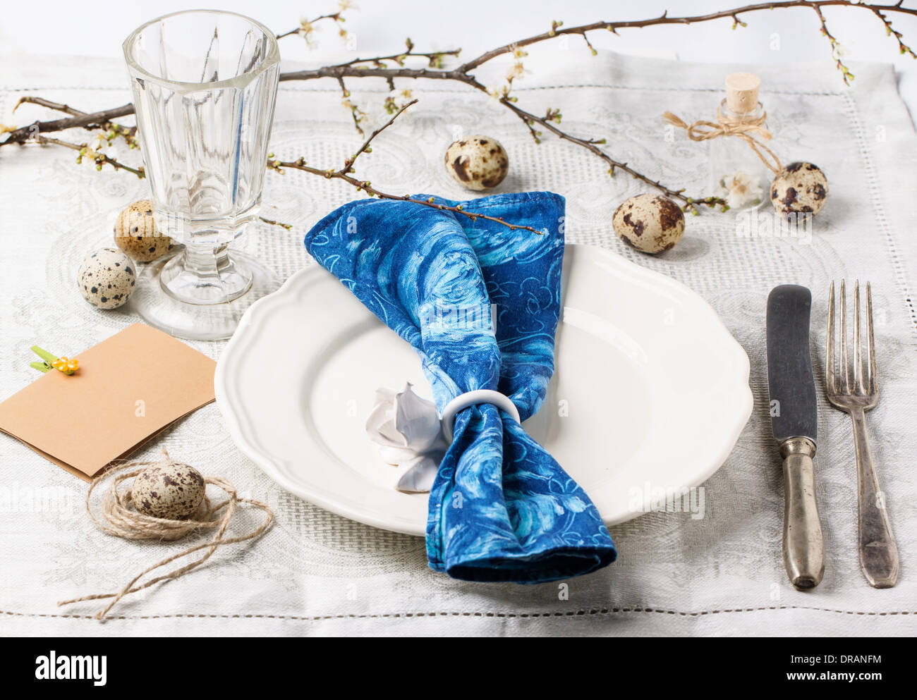 Easter table setting with vintage silverware, white plate, gray textile napkin, quail eggs and blossom branch on old wood Stock Photo