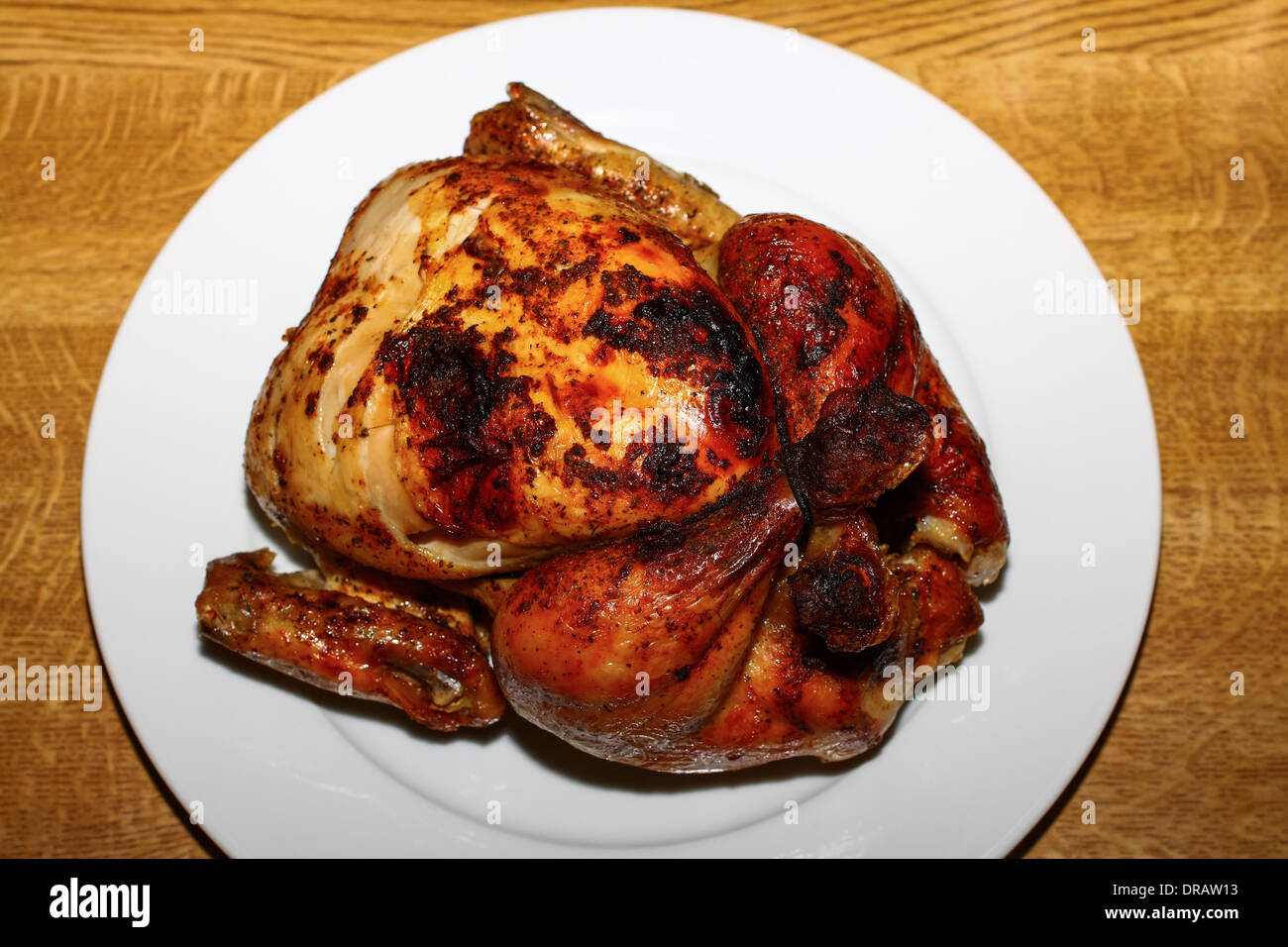 Whole roast chicken sat on a plain white plate Stock Photo - Alamy