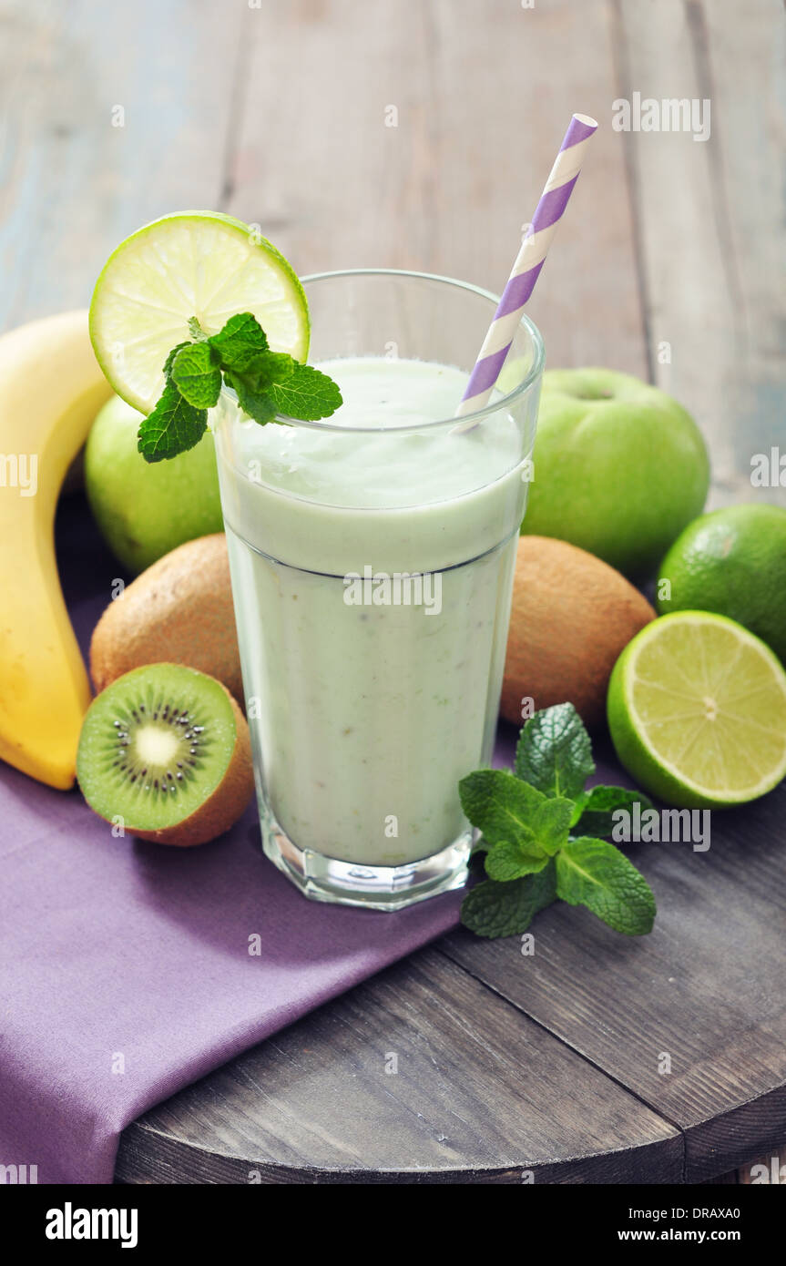 Banana smoothie with kiwi, apple, lime and mint on wooden background Stock Photo