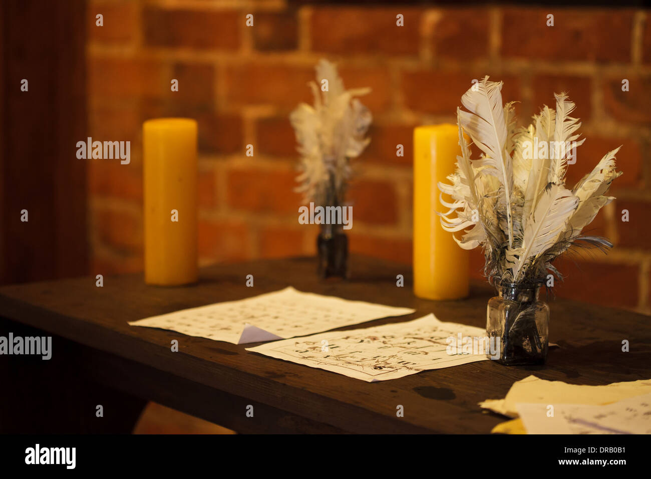 Writing. Feather quill pens, candle and old sheet of paper on wooden desk. Vintage retro style. Stock Photo