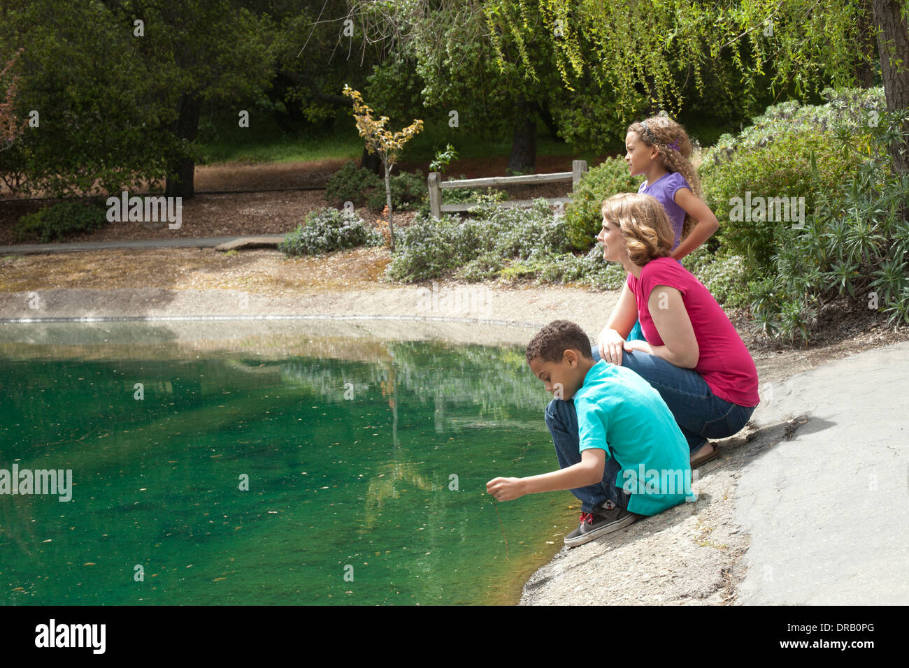Curious mother with children at riverbank Stock Photo