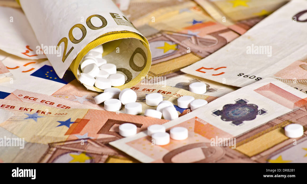European banknotes rolled with pills inside suggesting the cost involving medicine Stock Photo