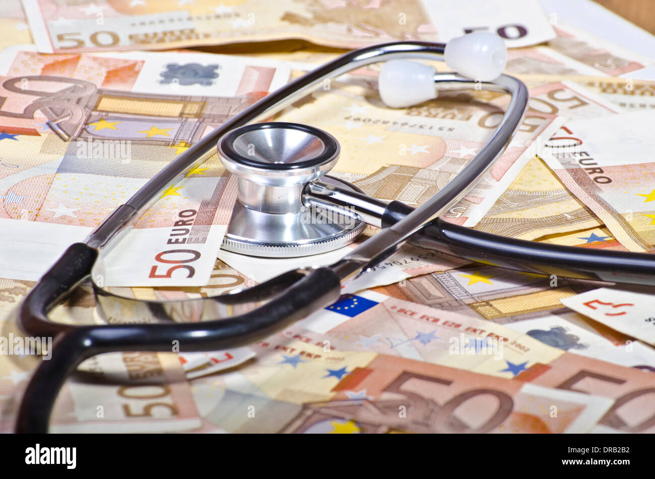 stethoscope surrounded by banknotes and coins suggesting the cost of medical investigation Stock Photo