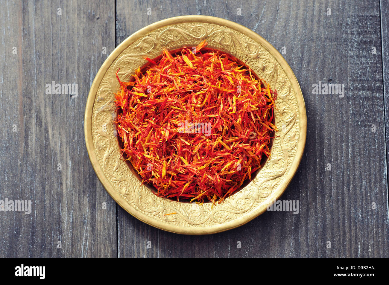 Saffron on golden plate on wooden background. Top view. Stock Photo
