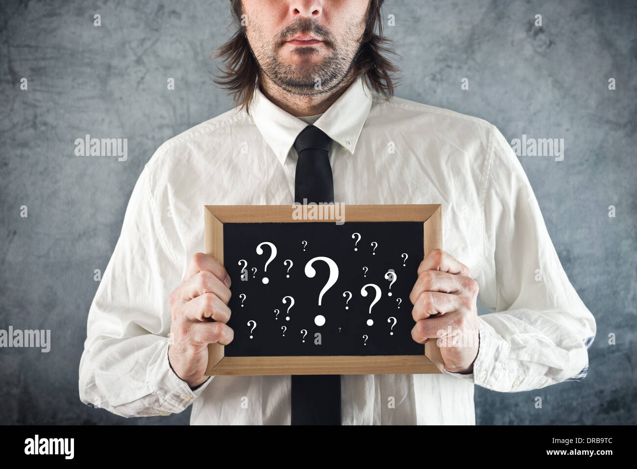 Businessman holding blackboard with question marks. Business questioning. Stock Photo