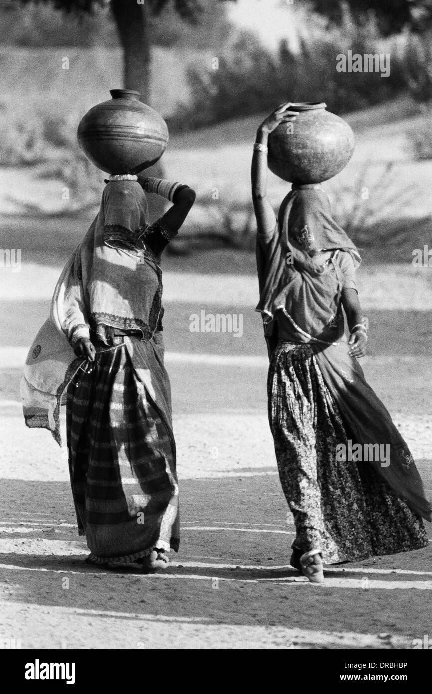 Woman women in ghunghat veil balancing water pots on head Udaipur Rajasthan India Asia Indian Asian 1976 old vintage 1900s picture Stock Photo