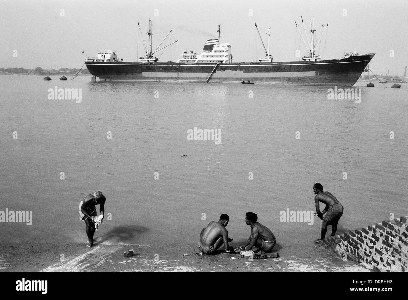 Men washing clothes Hoogly river with ship Kolkata West Bengal India Asia 1977 Stock Photo