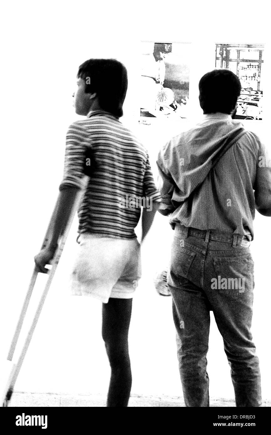 Man with a crutch at photography exhibition, Mumbai, Maharashtra, India, 1986 Stock Photo