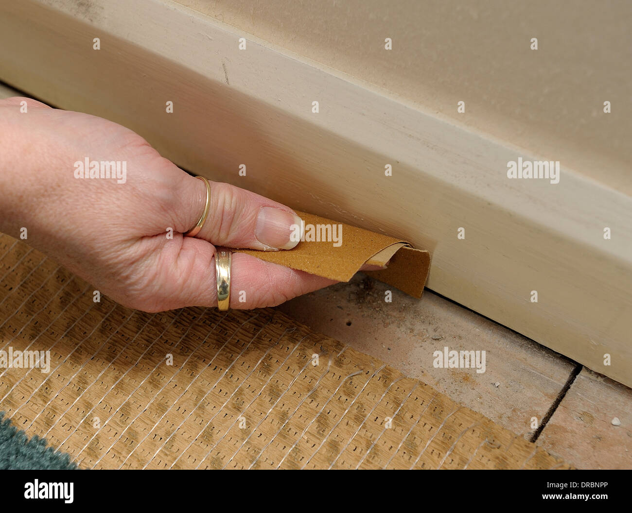 Female hand sanding down a painted skirting board Stock Photo