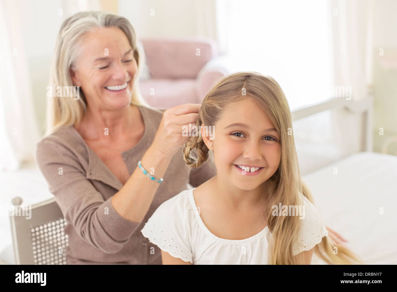 Grandmother braiding granddaughter's hair Stock Photo