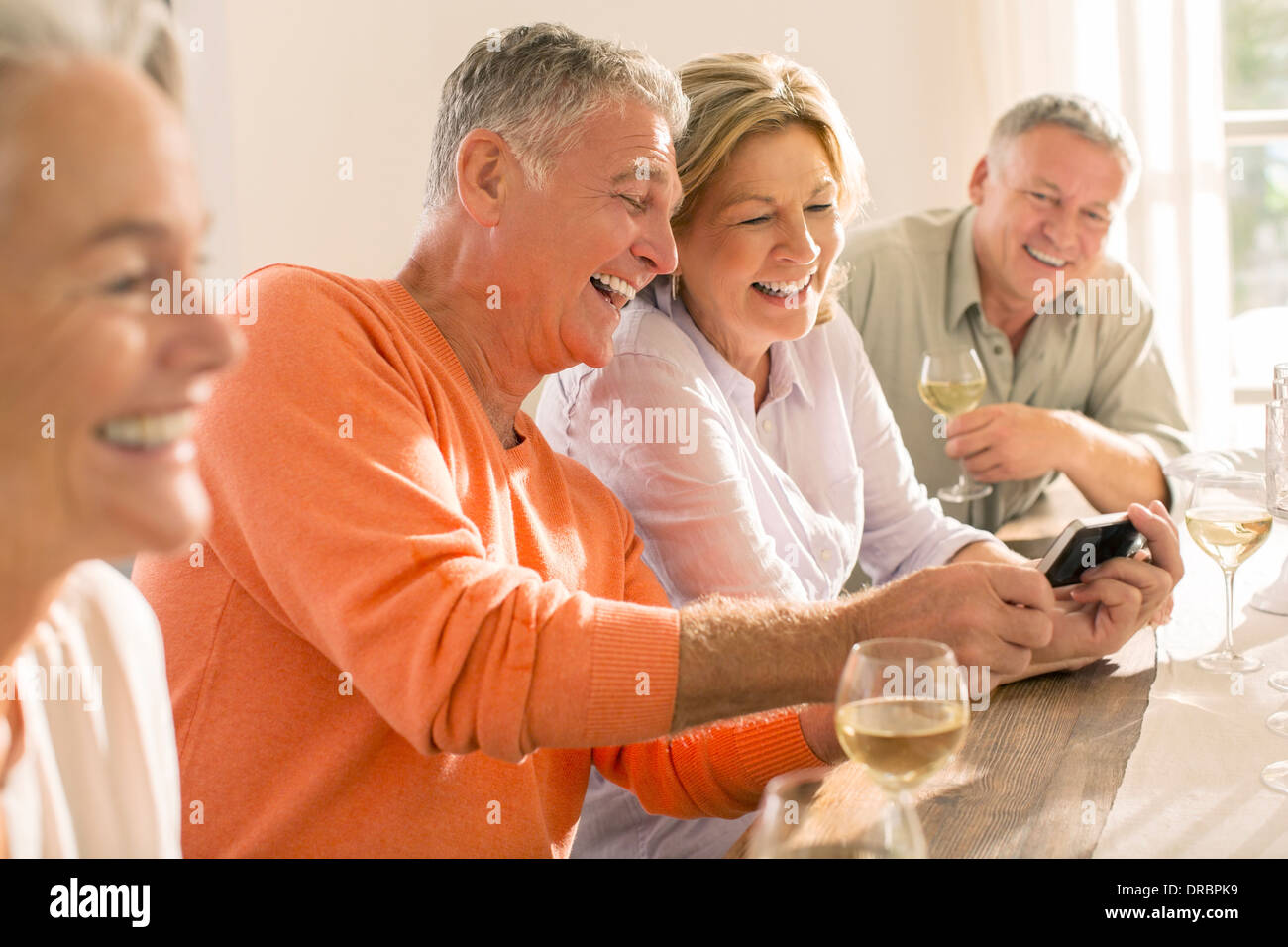 Senior couples drinking wine and looking at cell phone Stock Photo