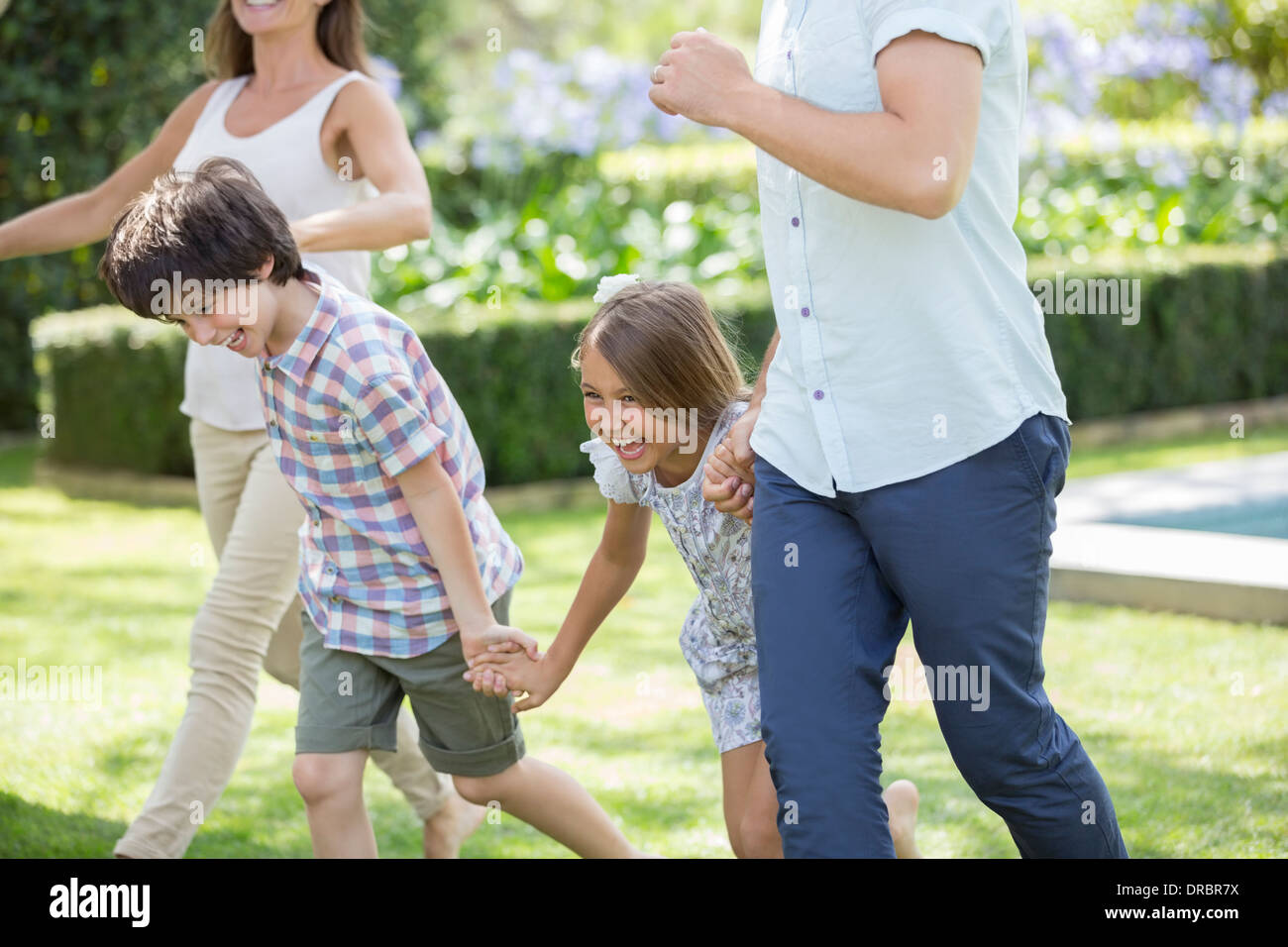 Family holding hands and running in backyard Stock Photo