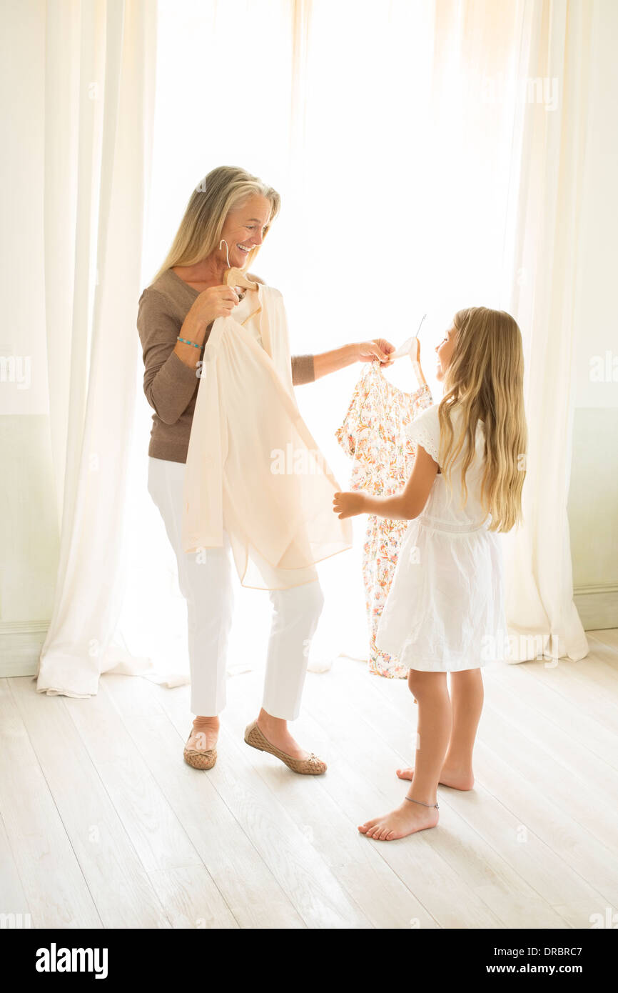 Grandmother and granddaughter holding clothing at window Stock Photo