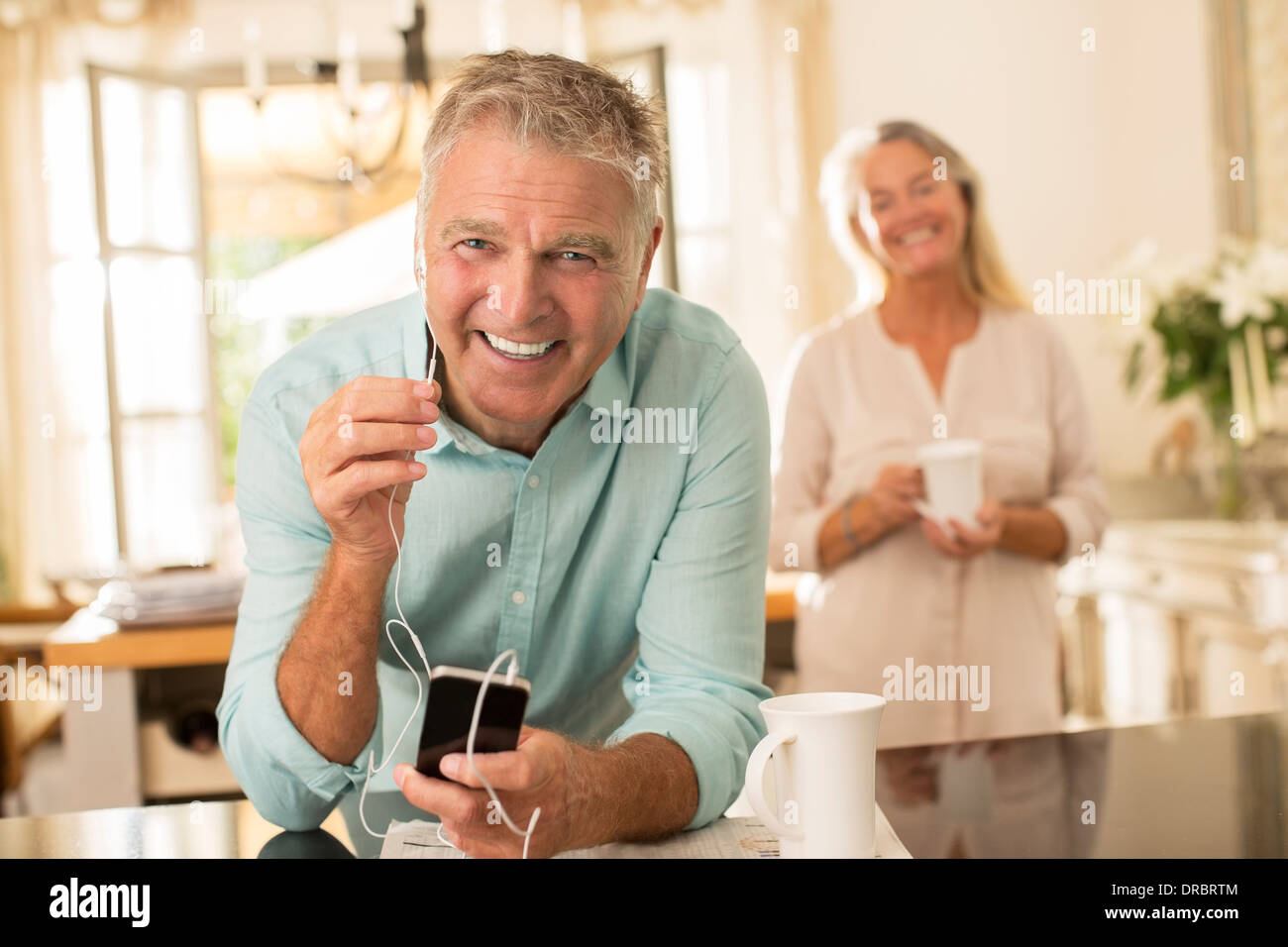Senior man listening to mp3 player in kitchen Stock Photo