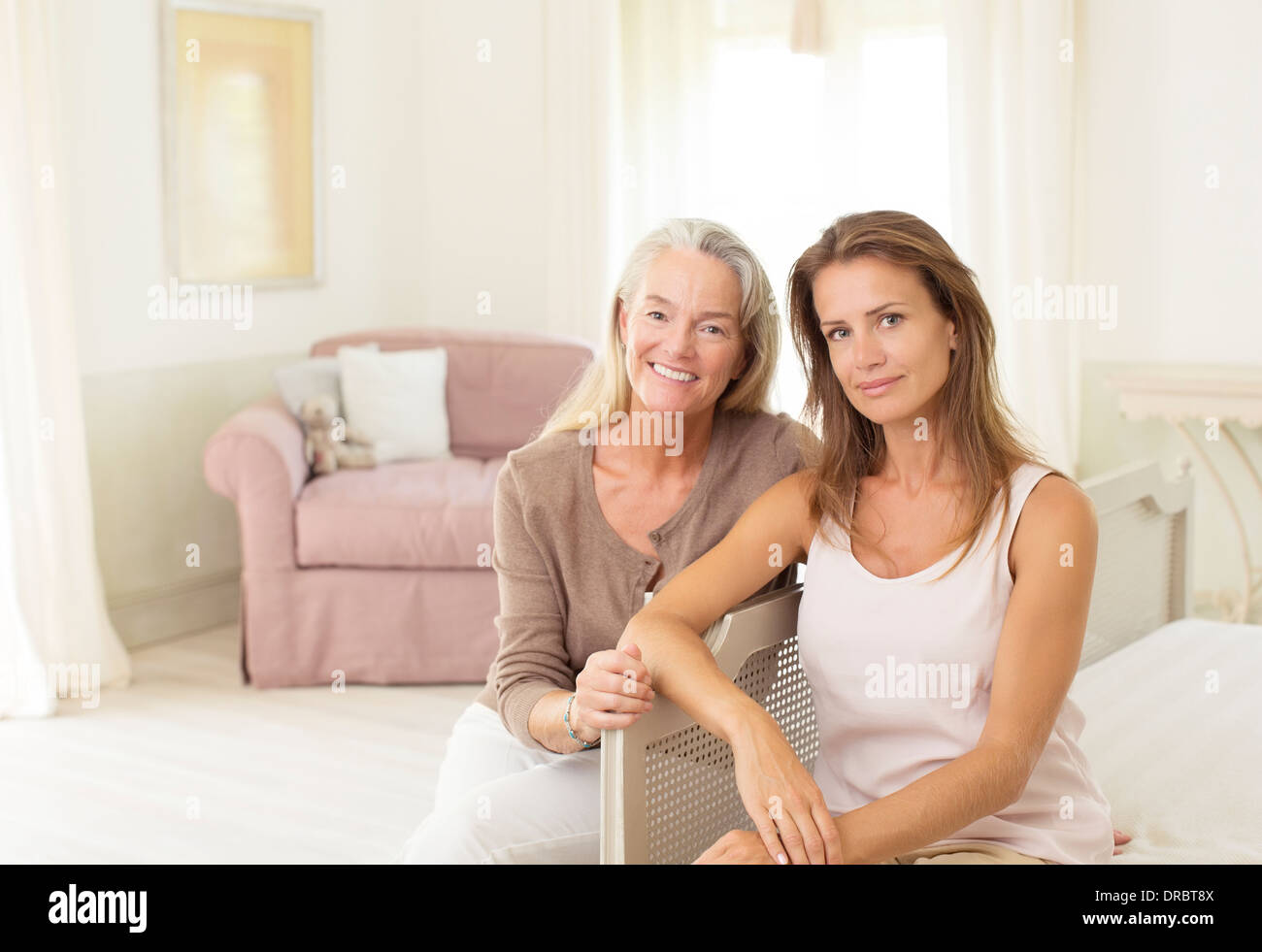 Mother and daughter smiling in bedroom Stock Photo