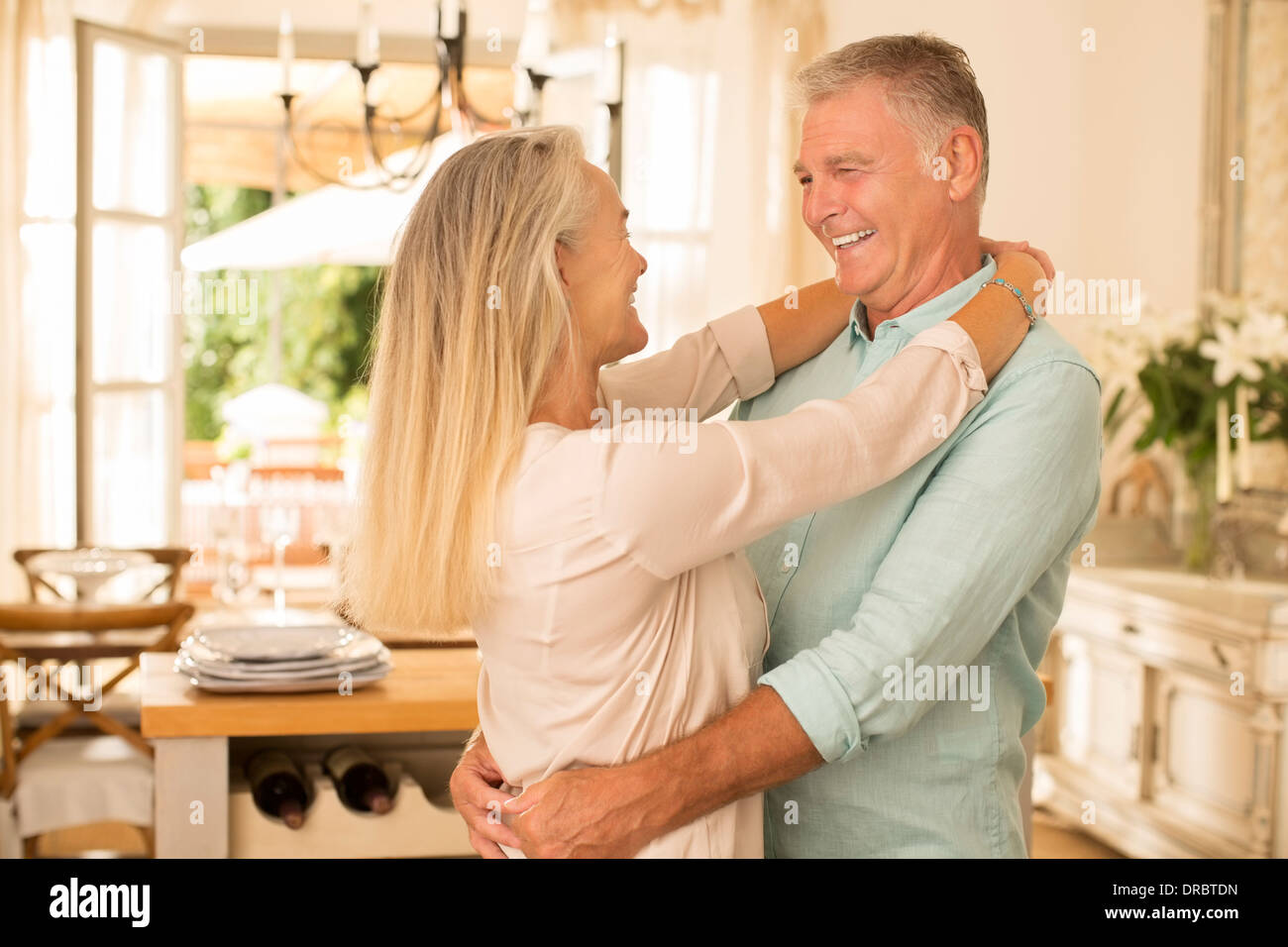 Senior couple hugging in kitchen Stock Photo
