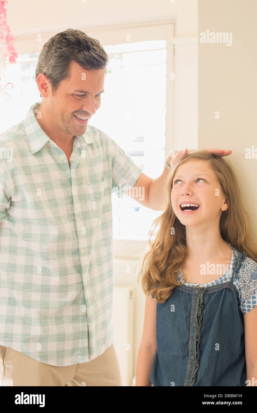Father measuring daughter's height on wall Stock Photo