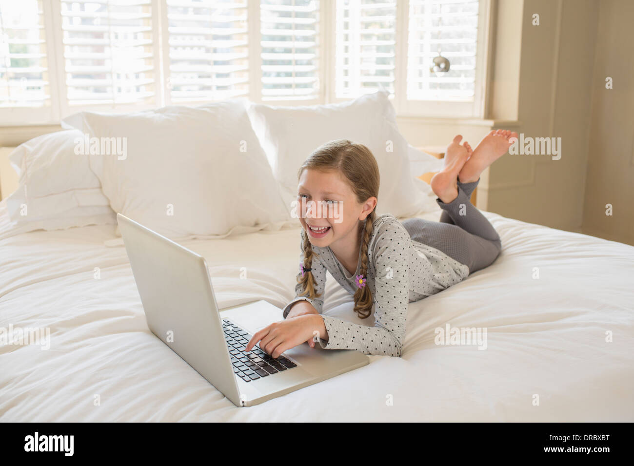 Girl using laptop on bed Stock Photo Alamy