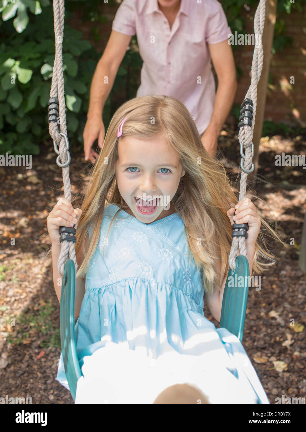 Father pushing daughter in swing Stock Photo