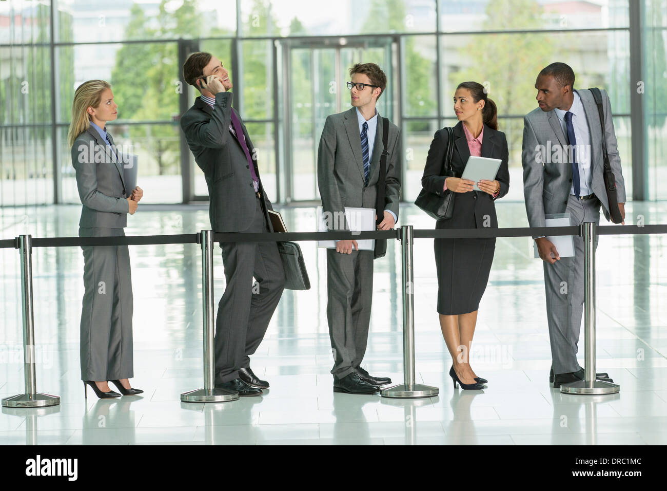 Businessman talking on cell phone in line Stock Photo