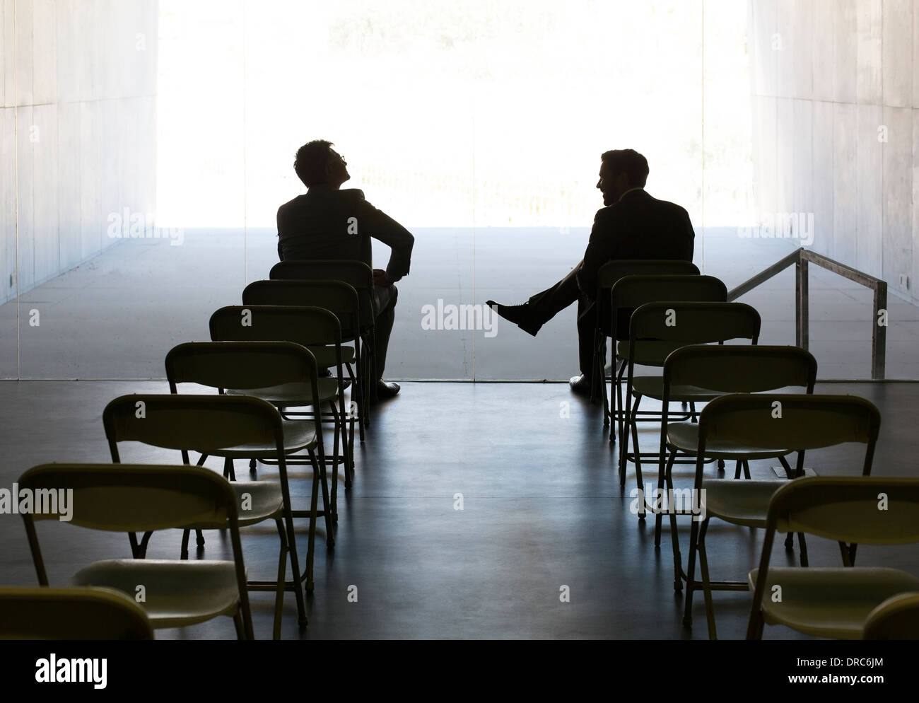 Businessmen talking at chairs in a row Stock Photo