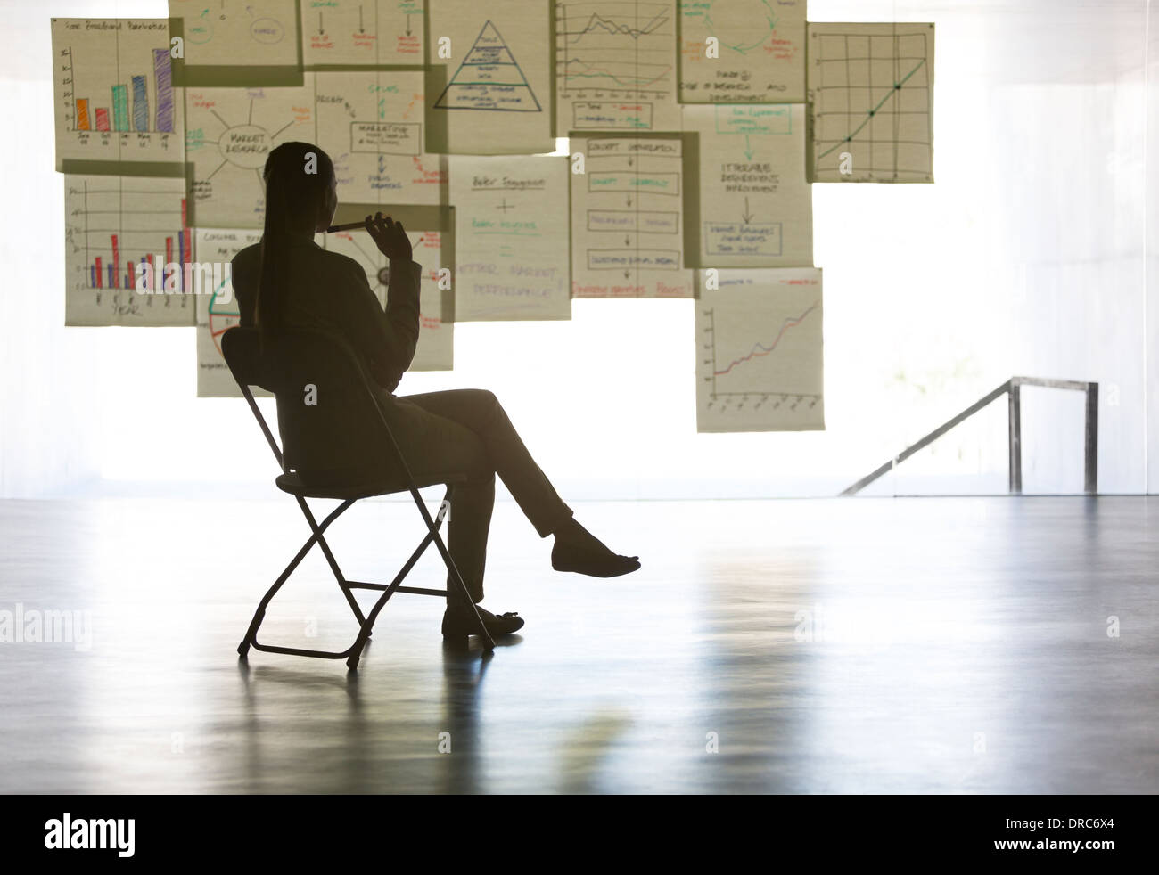 Businesswoman studying charts and graphs on wall in office Stock Photo