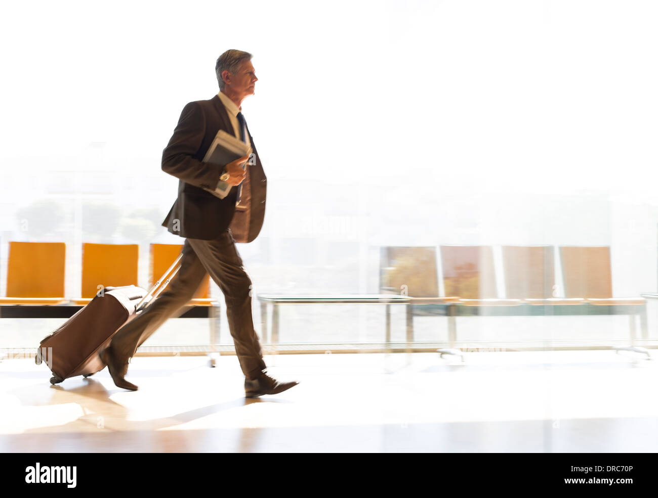 Businessman running with suitcase in airport corridor Stock Photo
