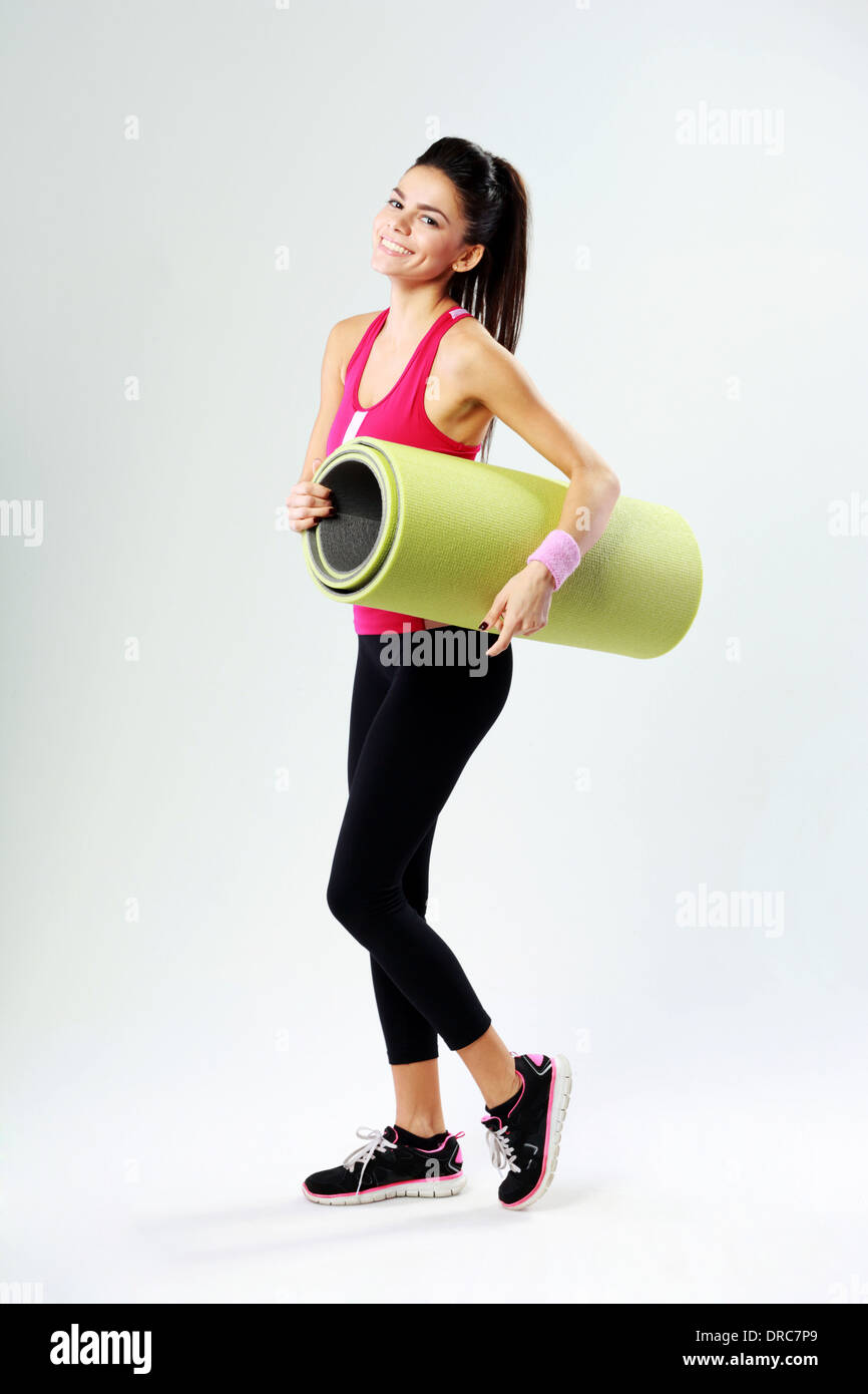 Young sport woman with yoga mat on gray background Stock Photo - Alamy