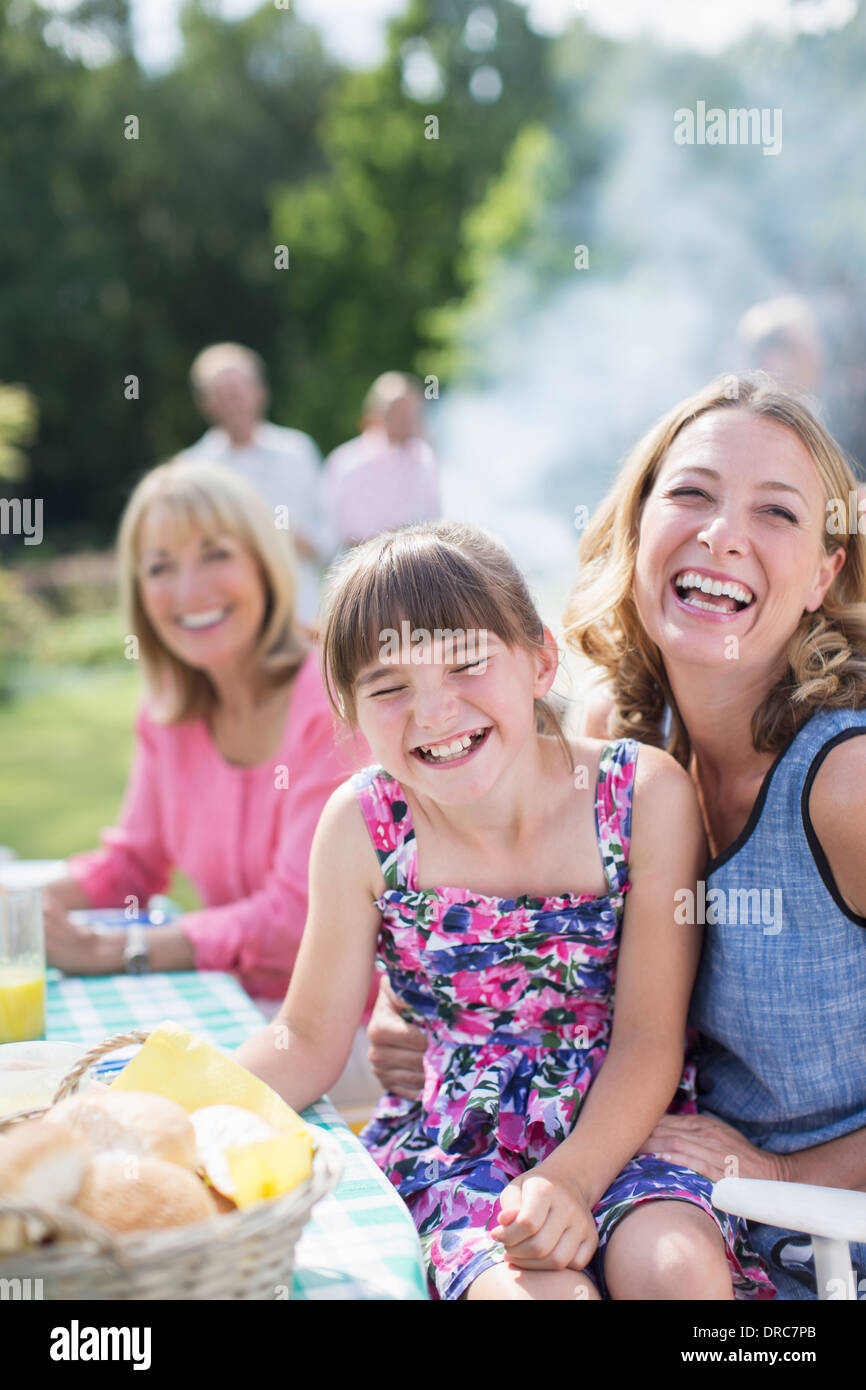 Mother and daughter laughing at table in backyard Stock Photo