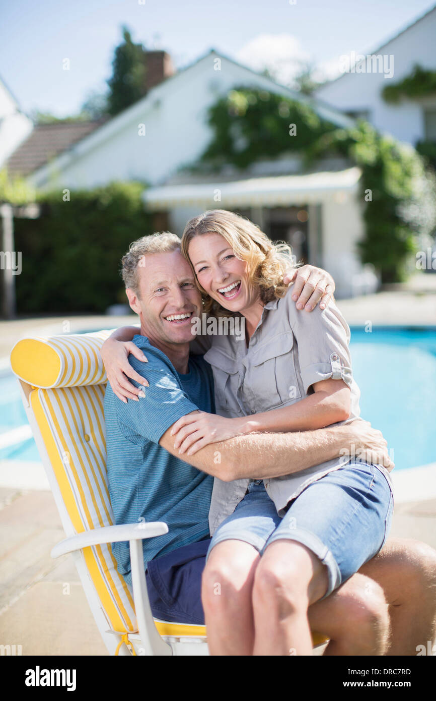 Couple sitting in lounge chair at poolside Stock Photo