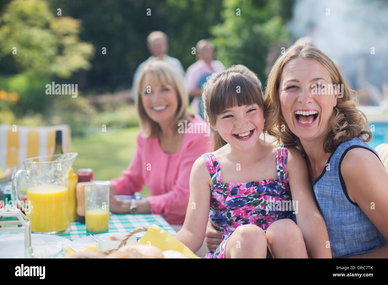 Multi-generation family laughing at table in backyard Stock Photo