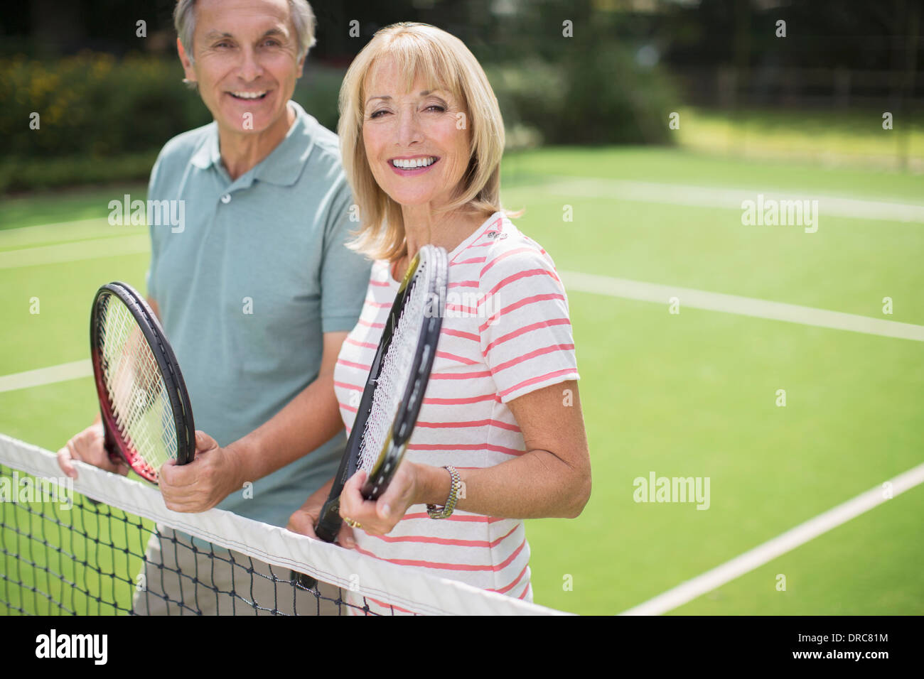 Couple smiling on tennis court Stock Photo