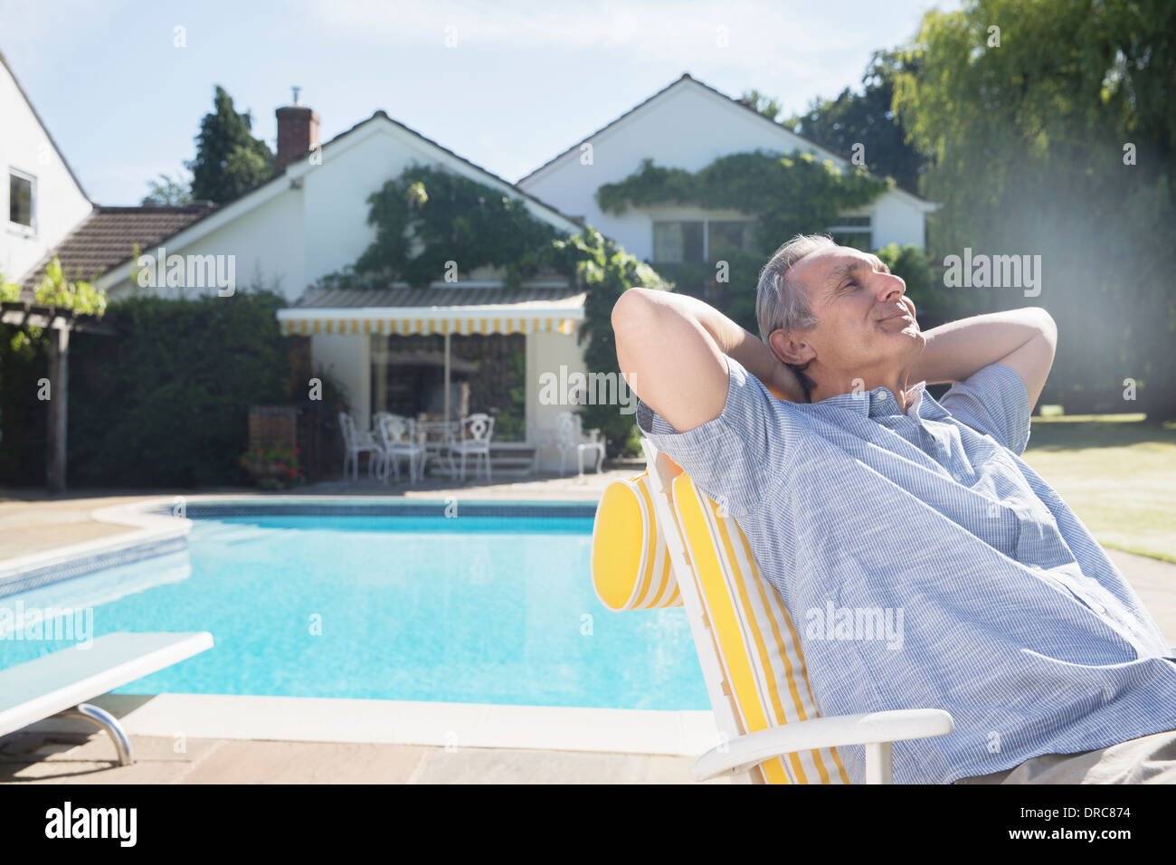 Man relaxing in lounge chair at poolside Stock Photo