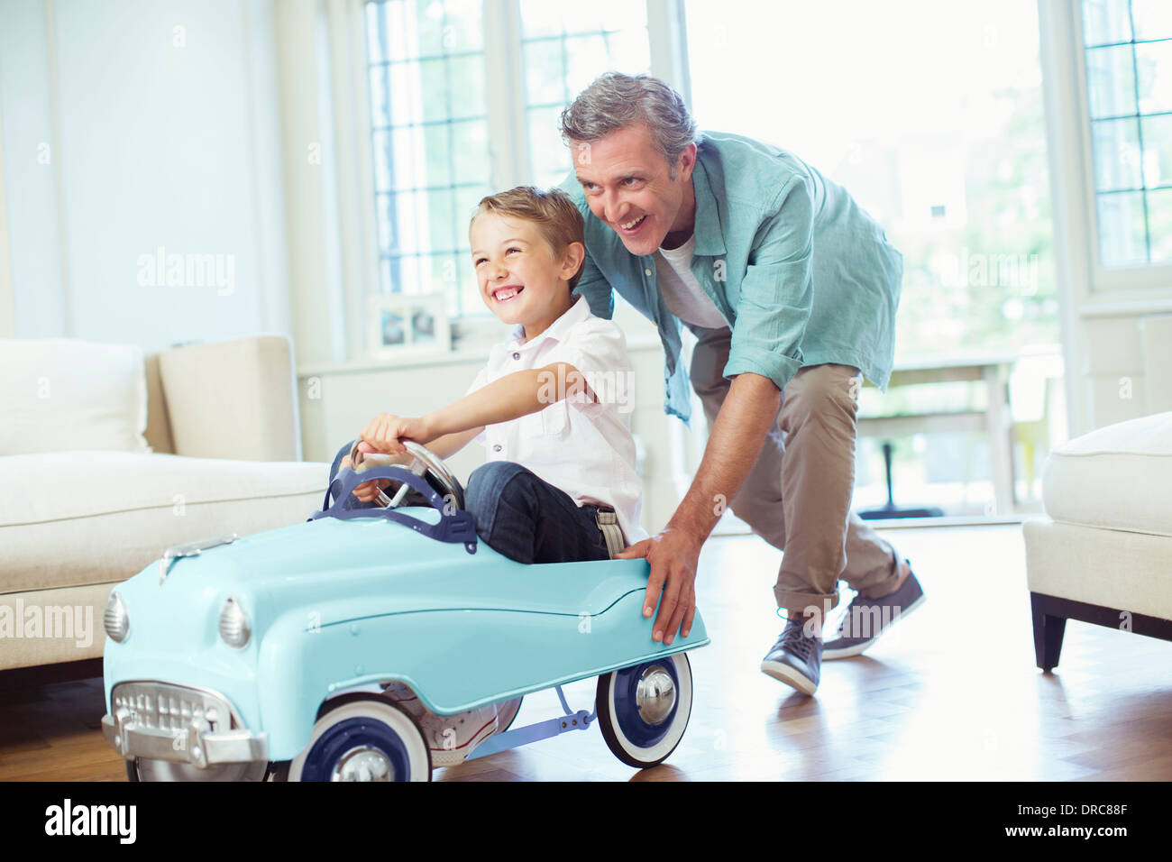 Father pushing son in toy car Stock Photo