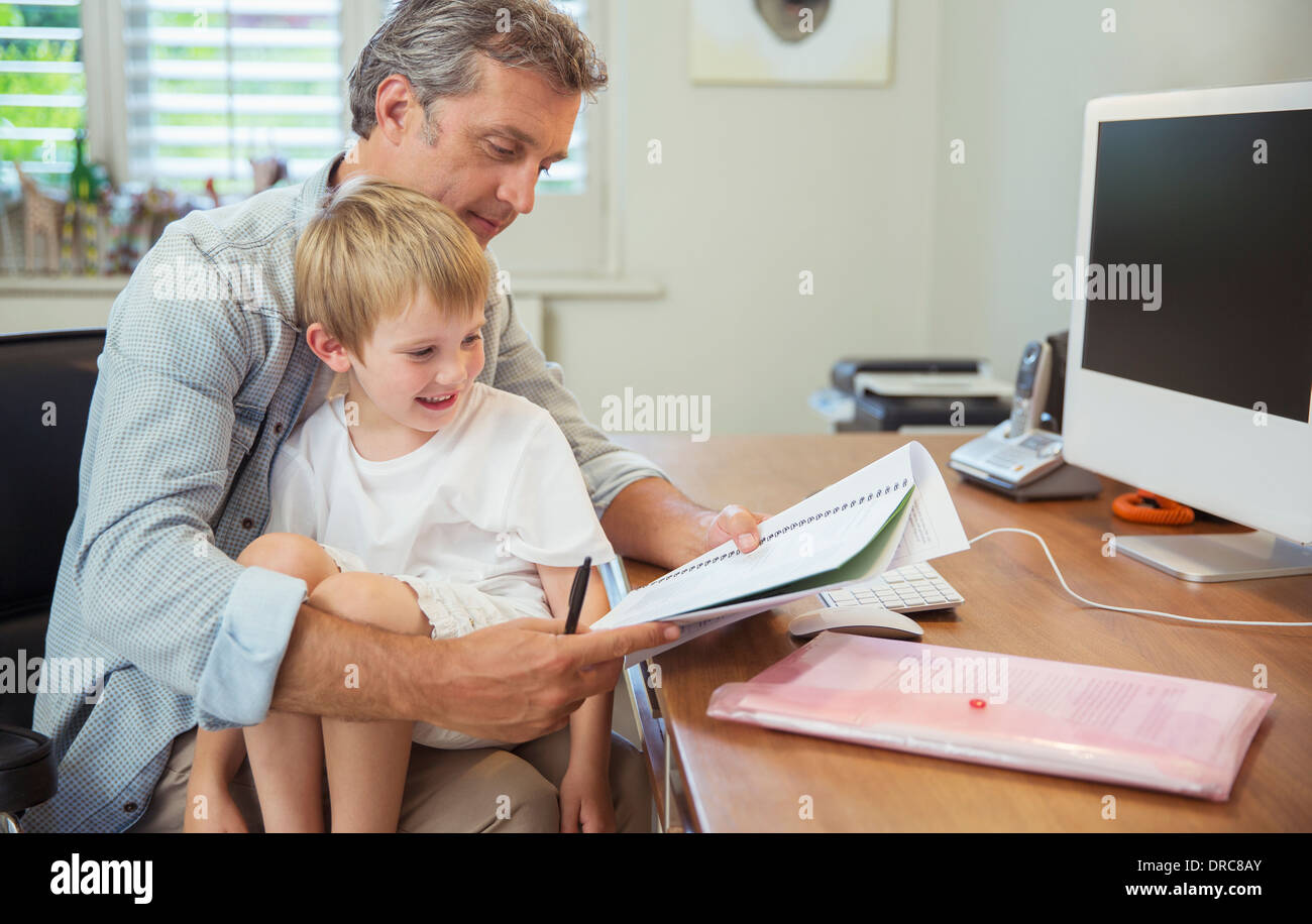 Son sitting on working father's lap Stock Photo