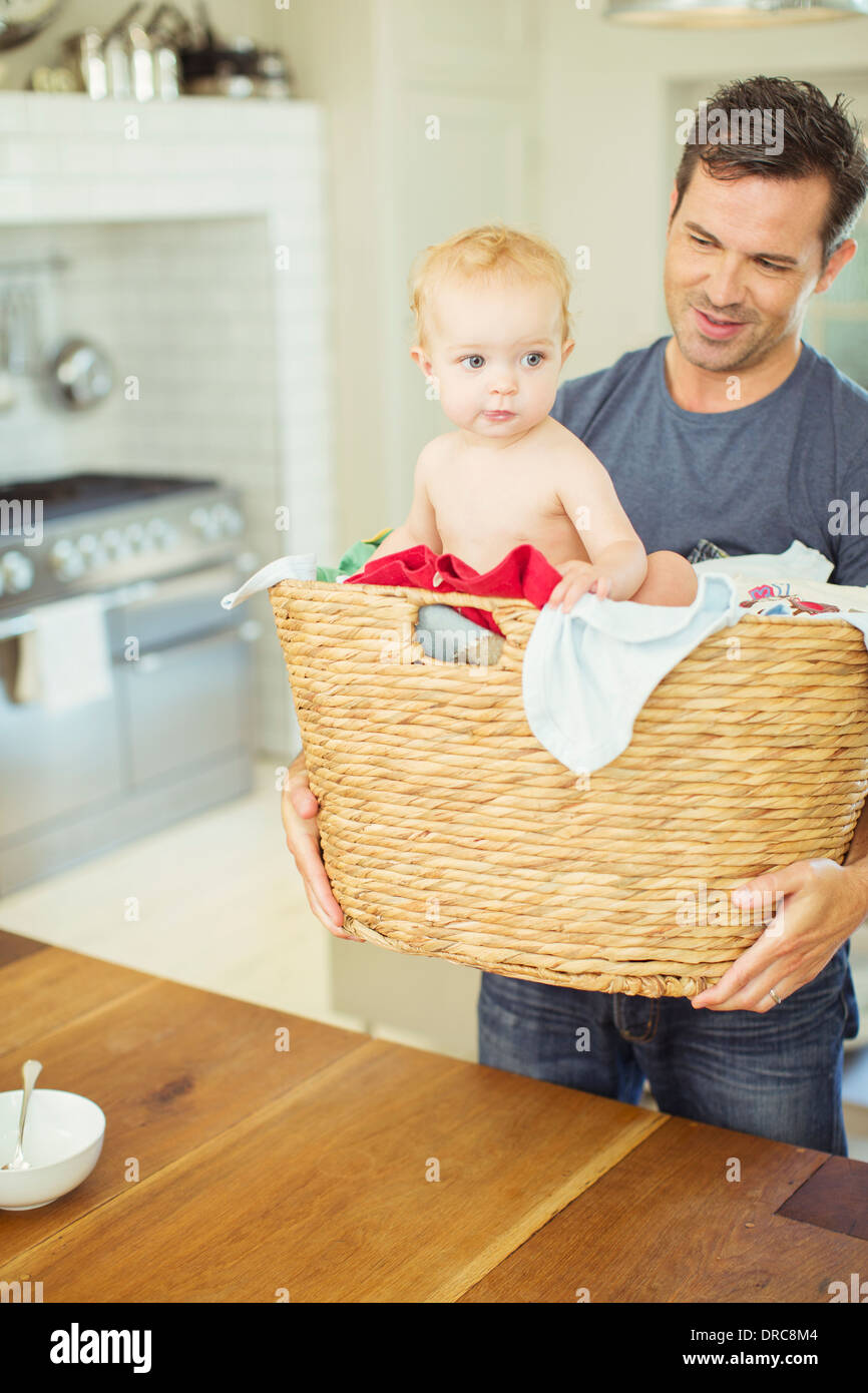 Father carrying baby in laundry basket Stock Photo Alamy