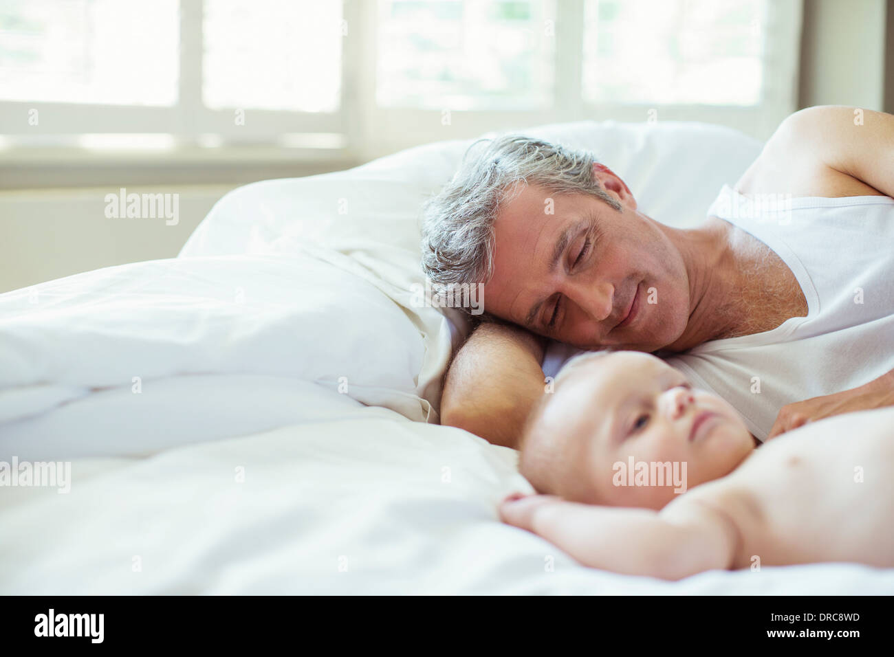 Father and baby laying on bed Stock Photo