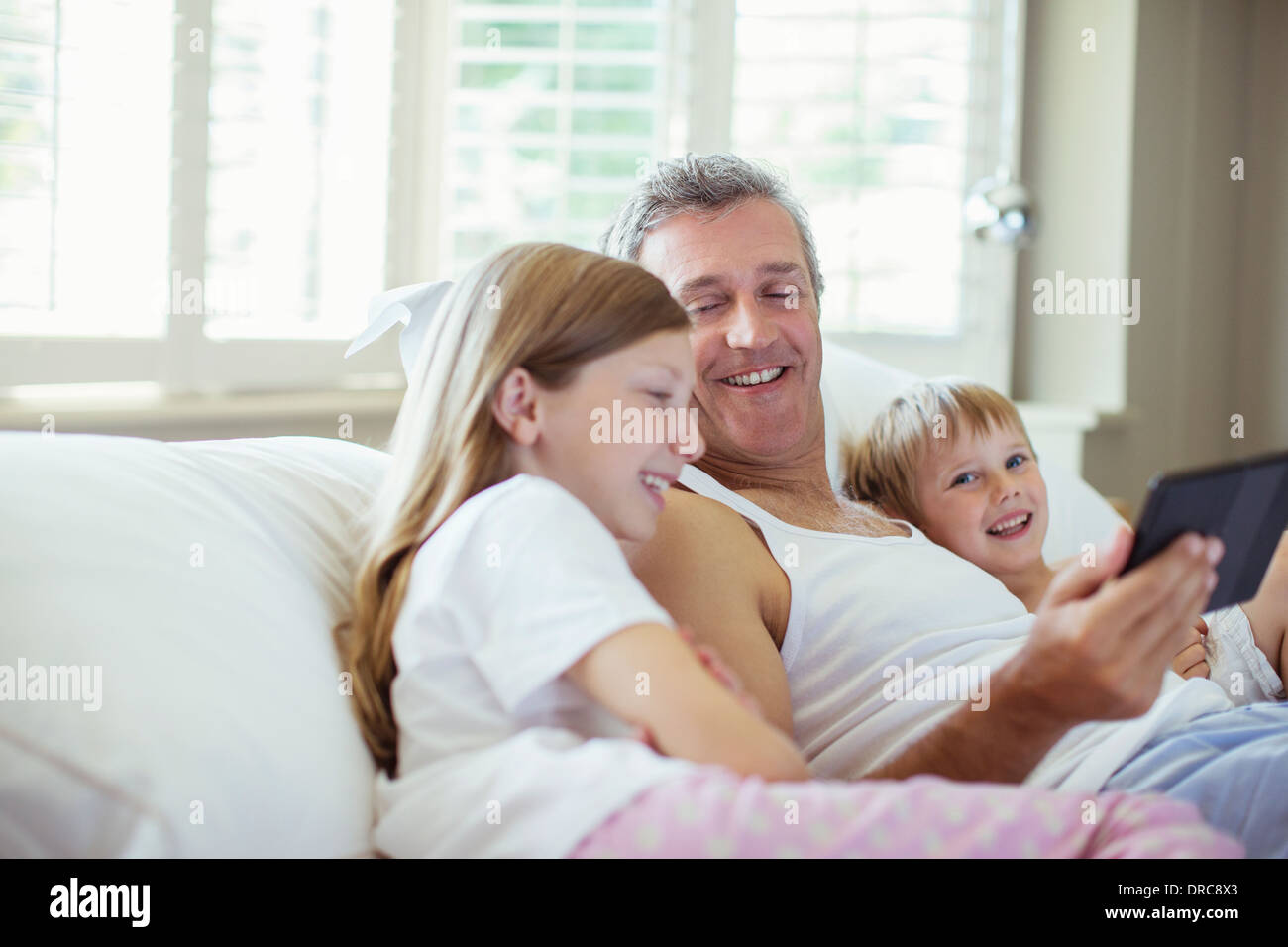 Father and children using digital tablet on bed Stock Photo