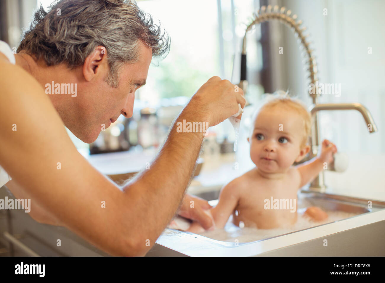 Father bathing baby in kitchen sink Stock Photo Alamy