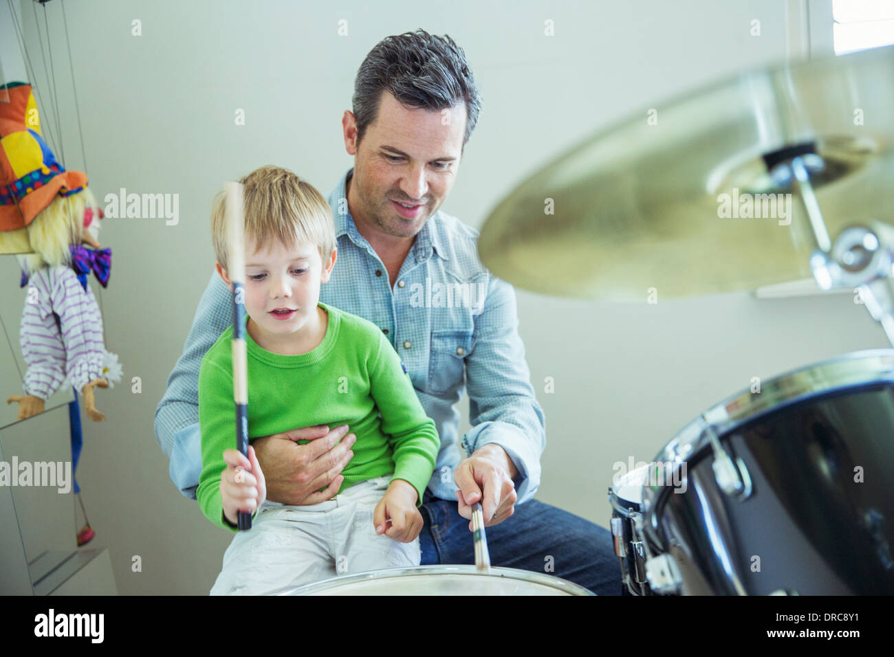 Father and son playing drums together Stock Photo