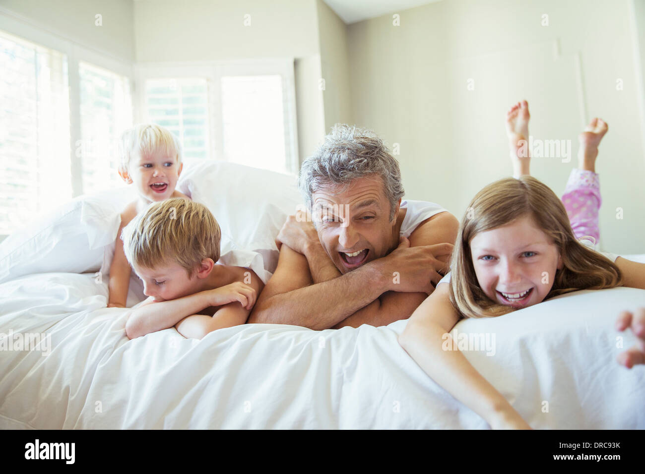 Father and children relaxing on bed Stock Photo
