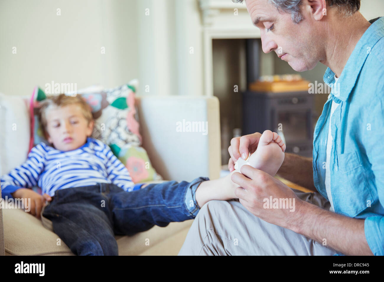 Father bandaging son's foot Stock Photo
