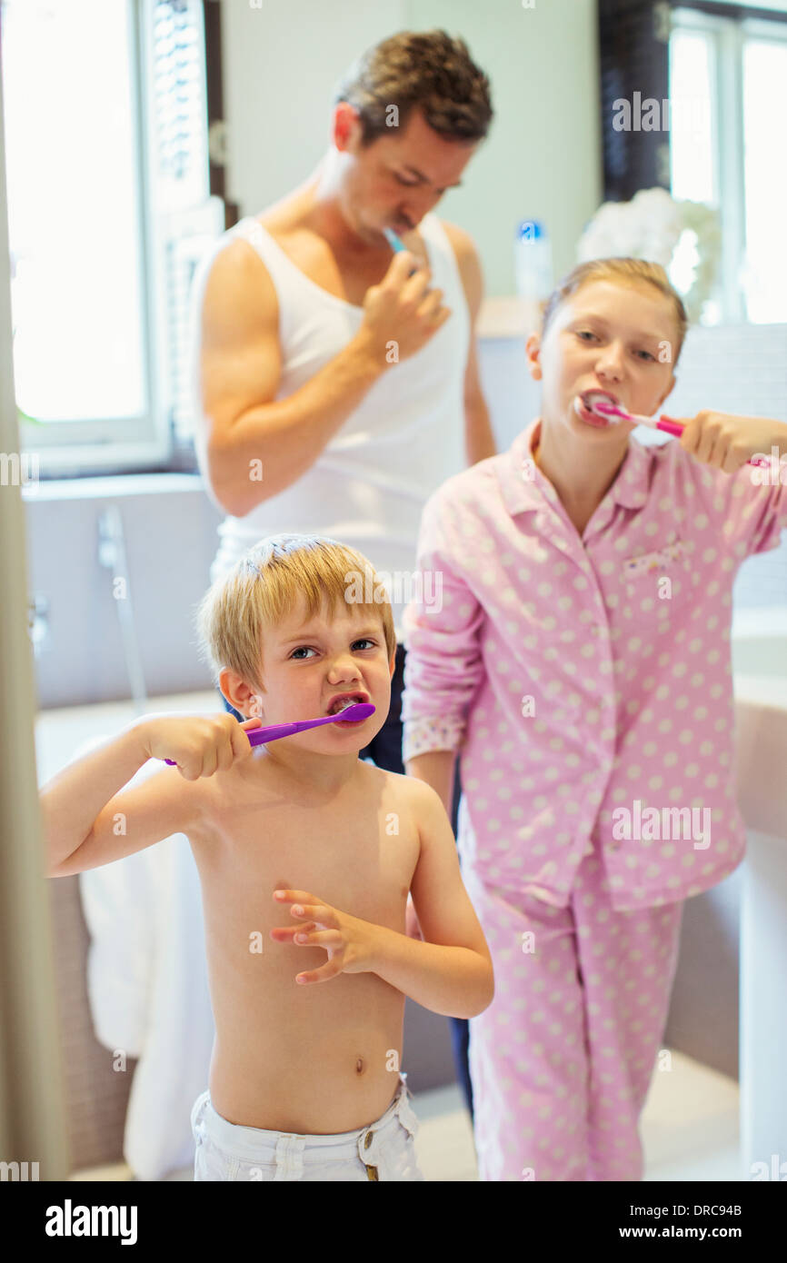 Father and children brushing teeth in bathroom Stock Photo