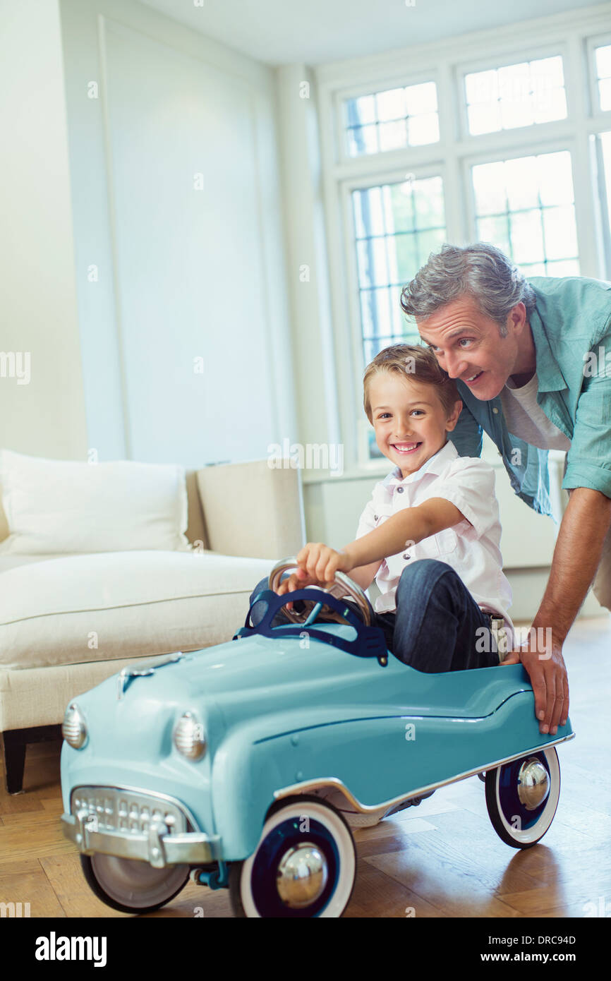 Father pushing son in toy car Stock Photo