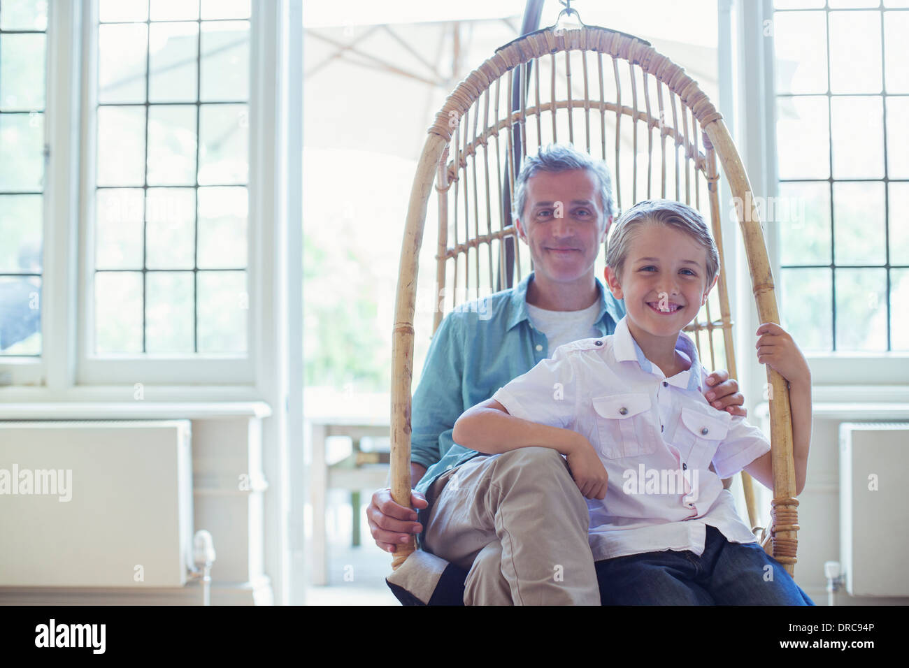 Father and son sitting in wicker chair Stock Photo