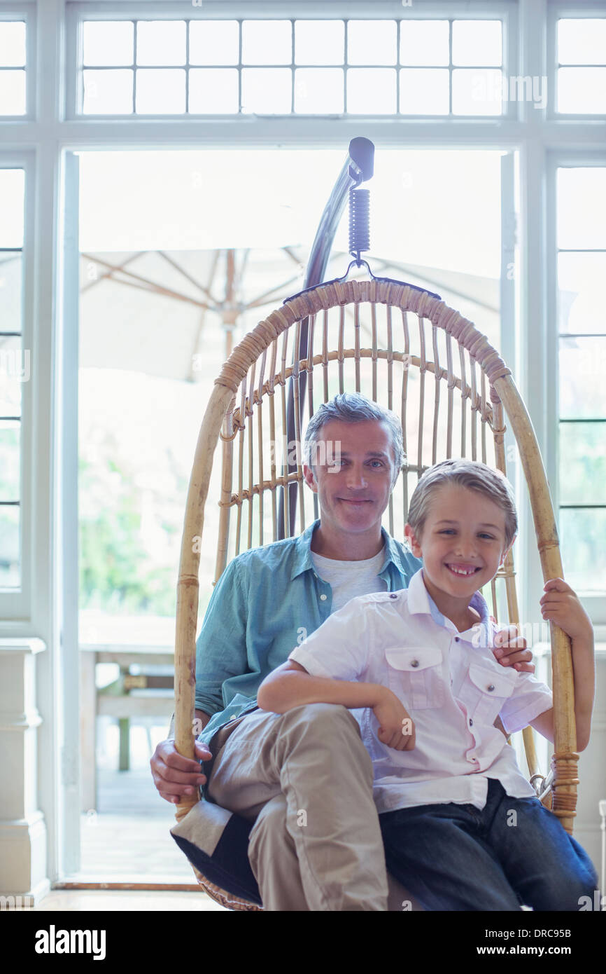Father and son sitting in wicker chair Stock Photo