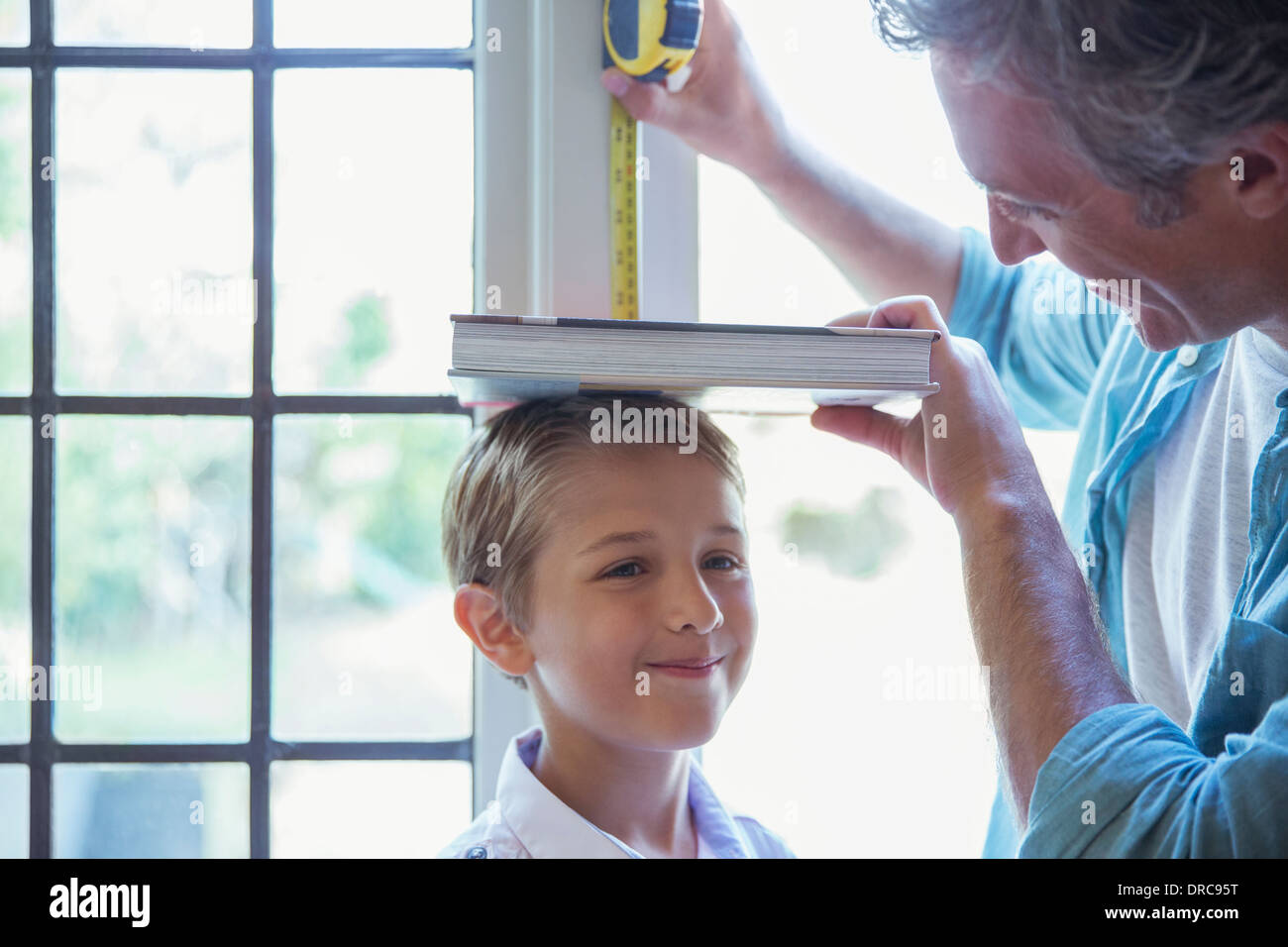 Father measuring son's height on wall Stock Photo