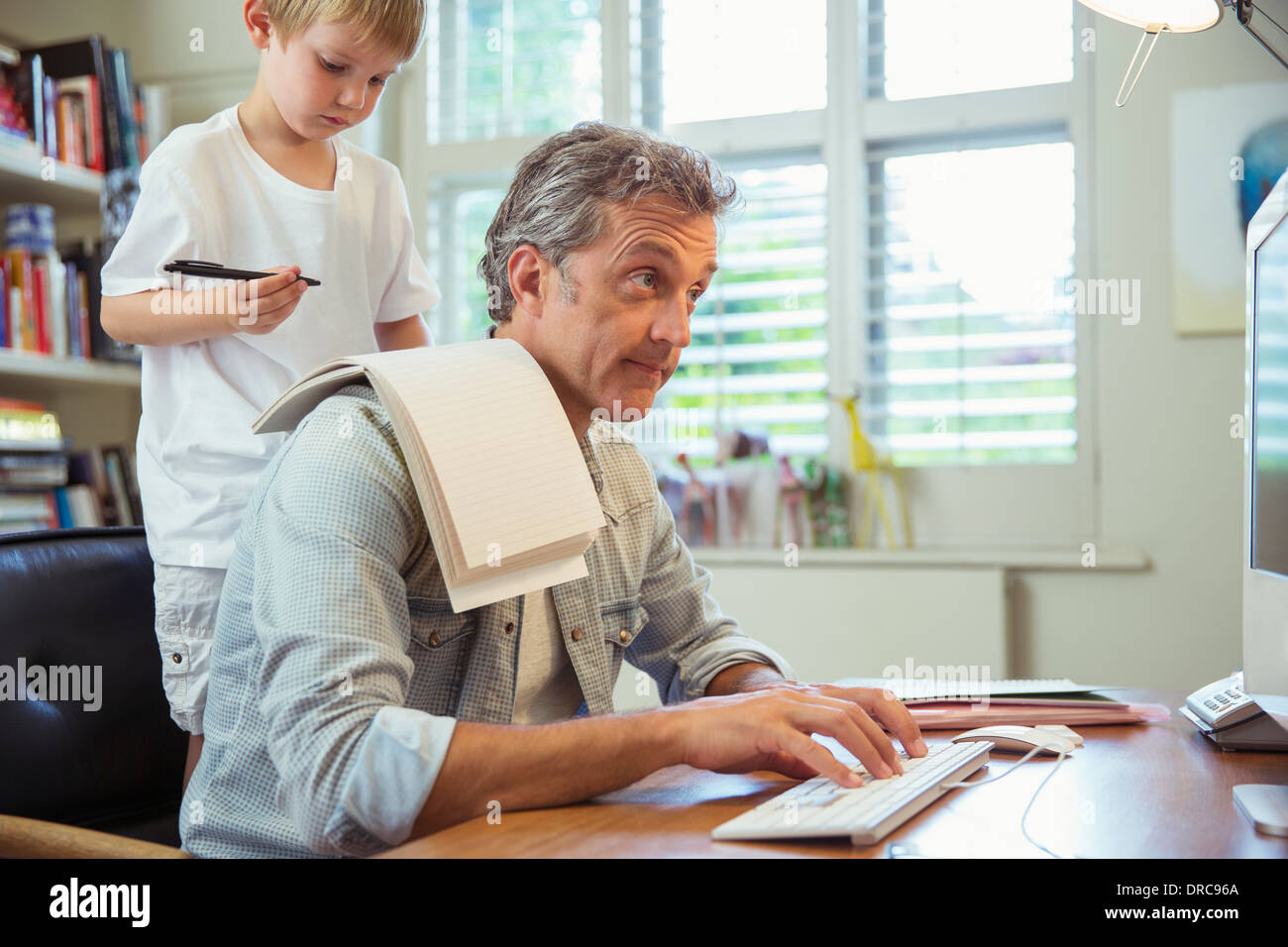 Son distracting father at work in home office Stock Photo
