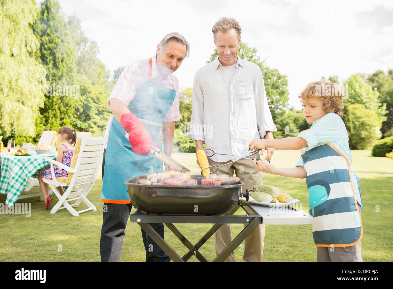 Men grilling meat on barbecue in backyard Stock Photo